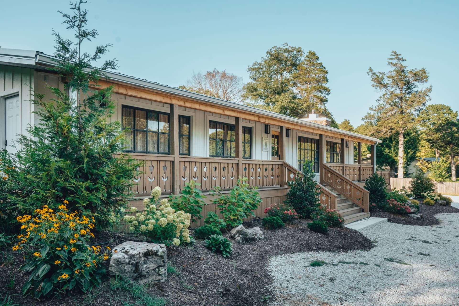 The covered front porch and flower gardens at Sommer House Inn on a sunny morning, Jasper AR