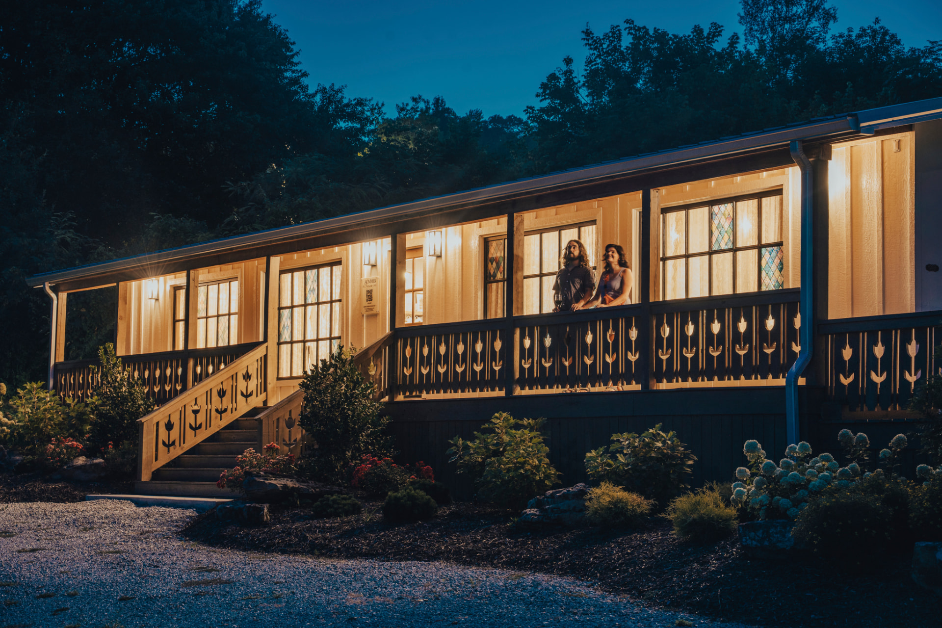 Sommer House Inn illuminated at dusk in Jasper, Arkansas, with guests on the front porch